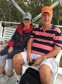 a photo of Elizabeth and Peter sitting side by side on the boat smiling at camera