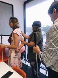 image shows Kim guiding one of the radio hosts at radio studio, with two other staff behind applying sighted guide