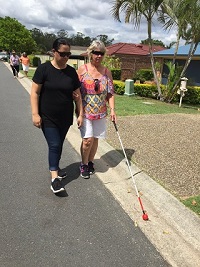 a support Worker waring a blindfold sighted guide and cane