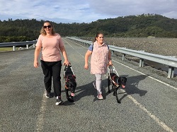 Hinze Dam Tarhnee & Hailey, Tarhnee and Hailey walking side by side on top of Hinze Dam wall with their black dog guides
