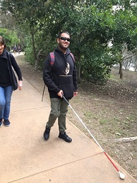 Kushal walking with a long cane extended