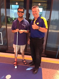 Kushal standing next to G-link staff with a tram behind them
