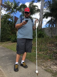 Picture of Justin standing with smart phone in one hand and smart cane in the other preparing navigation function