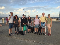 Redcliffe Pier, Standing on the pier side by side is Jack, Tarhnee, Jordy, Hailey, Jenny, Peter & Kim, one white cane and two black dog guides